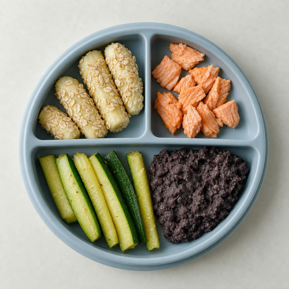 Baby-led weaning plate with banana, salmon, zucchini, and black beans