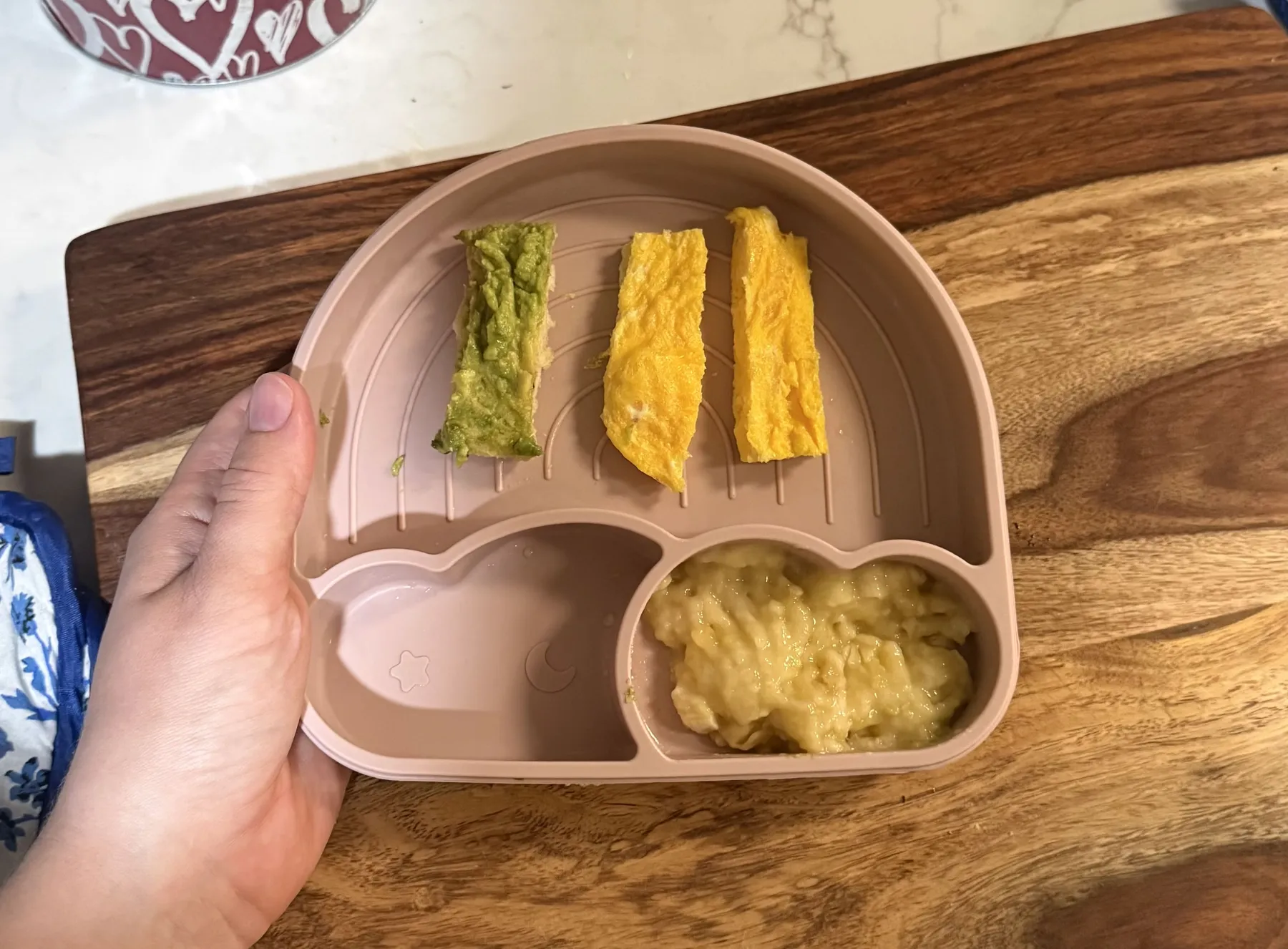 A parent-shared plate of avocado toast, egg strips, and mashed banana
